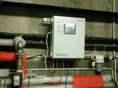 Wall-mounted Envirolyte generator connected to water-treatment piping in a plant room