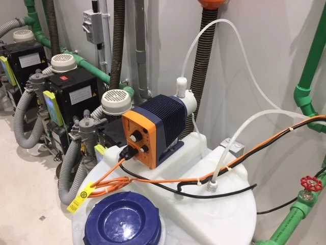 Anolyte dosing pump mounted above a solution tank at a dental clinic