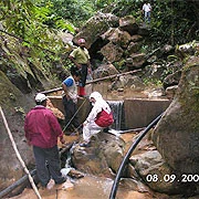 Workers preparing a rural water intake at a rocky stream
