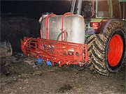 Tractor carrying liquid containers and a spray boom for silage treatment