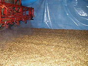 Spray boom positioned above chopped forage in a covered silage bunker
