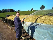 Worker holding a spray hose beside an open silage bunker